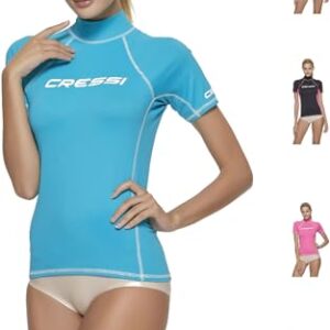 Frau in einem blauen Rash Guard mit dem Logo Cressi auf ihrem Top. Sie hält ihre Hand zum Kinn und zeigt eine selbstbewusste Pose. Im Hintergrund ist weiß.
